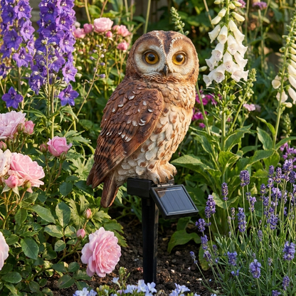Solar owl stake light among cottage garden flowers in daylight