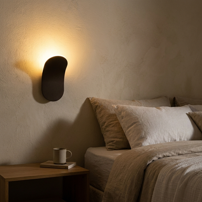 Minimalist LED wall lamp glowing beside a bed at night