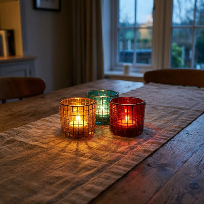 Mosaic glass candle holders lit on a dining table at dusk